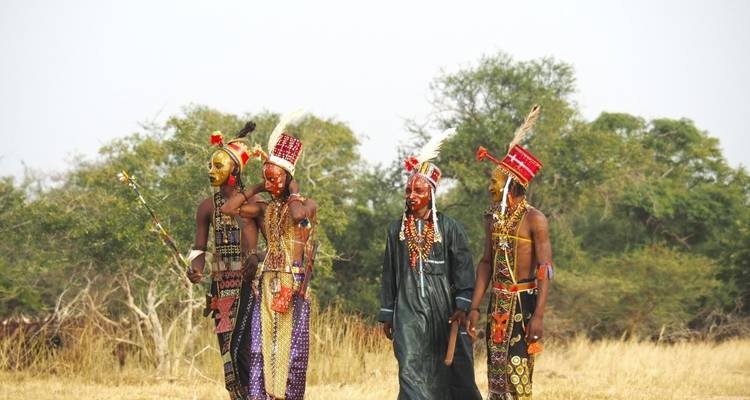 Four people in traditional attire walking on an open field.