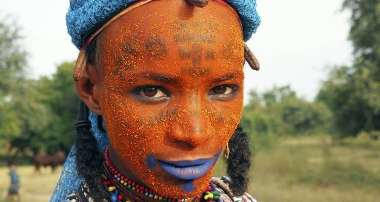 Close-up of face with orange face paint and beads.