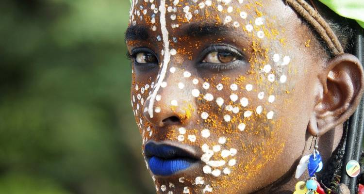 Close-up of a face adorned with face paint and colorful decor.