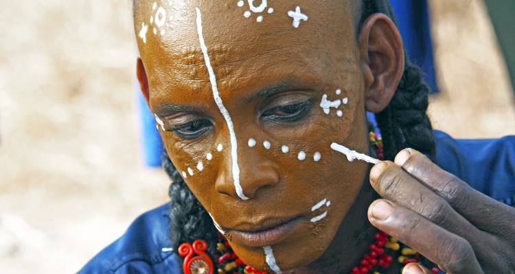 Close-up of a person applying decorative face paint.