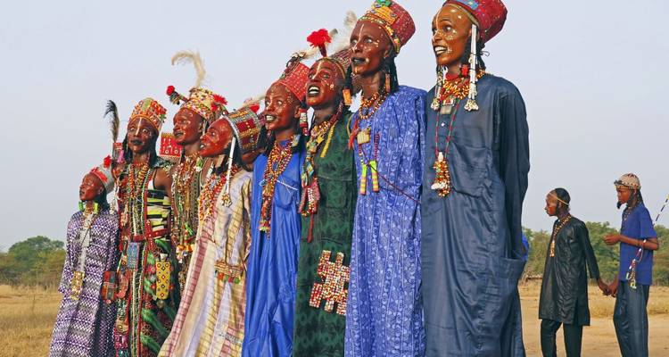 A group of colorfully dressed people standing in an open field.
