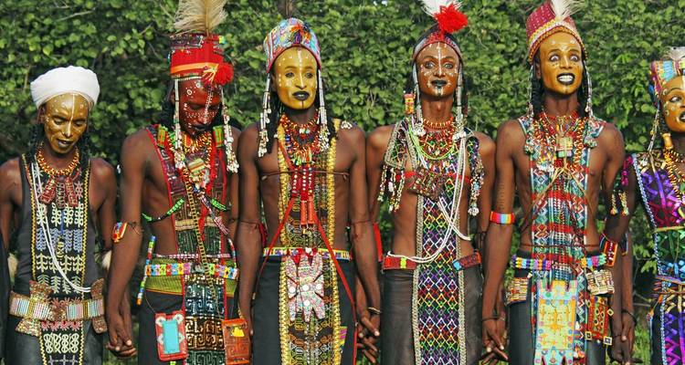 Group of people in colorful traditional dress holding hands.