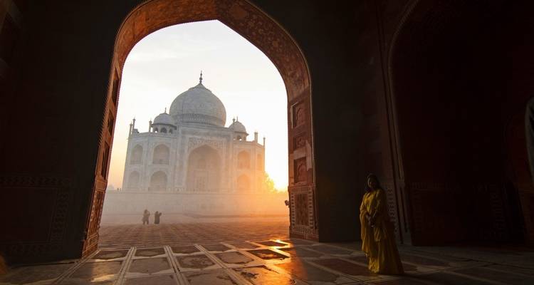 Blick auf das Taj Mahal durch einen Torbogen, mit einer stehenden Person.