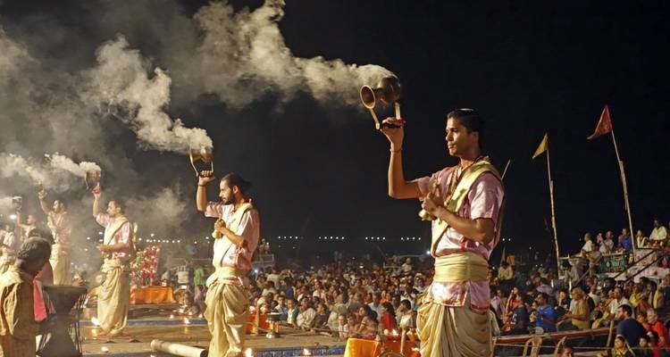 Abendgebetszeremonie am Flussufer mit einer Menschenmenge.