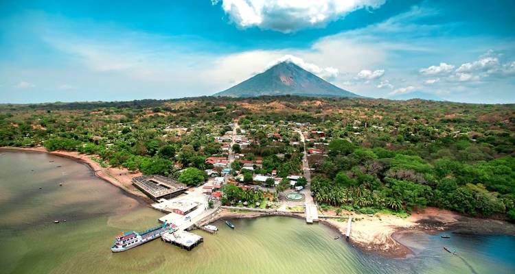 Aerial view of a village with a volcano in the background.