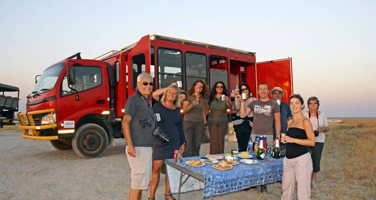Un groupe savourant de la nourriture à côté d'un véhicule de safari.
