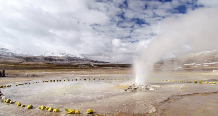 Géiser en erupción en un paisaje vasto y desolado.