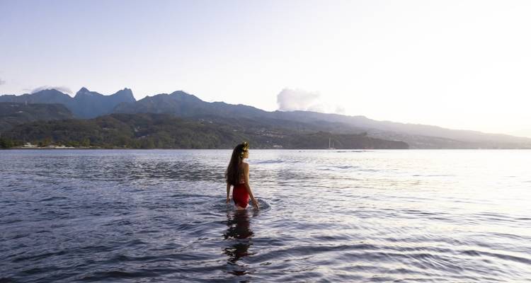 Persona de pie en agua poco profunda con fondo montañoso.