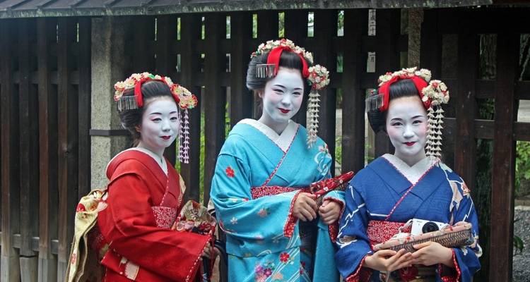 Tres mujeres en kimonos tradicionales posando al aire libre