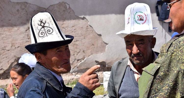 Two men in traditional hats having a discussion outdoors.