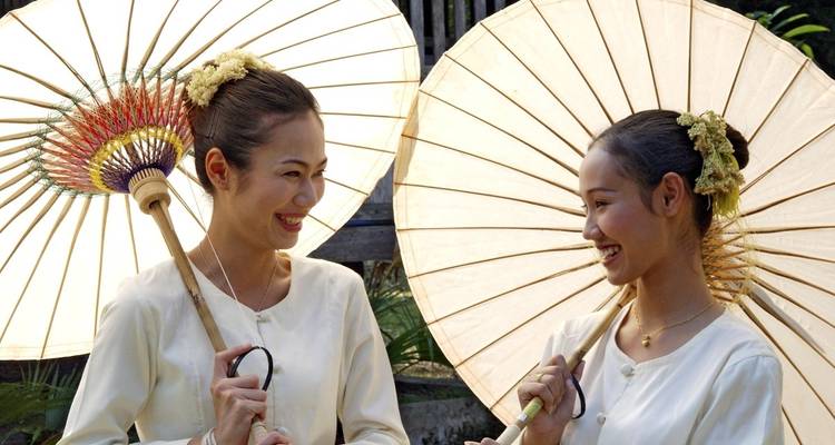 Two women smiling and holding traditional parasols.