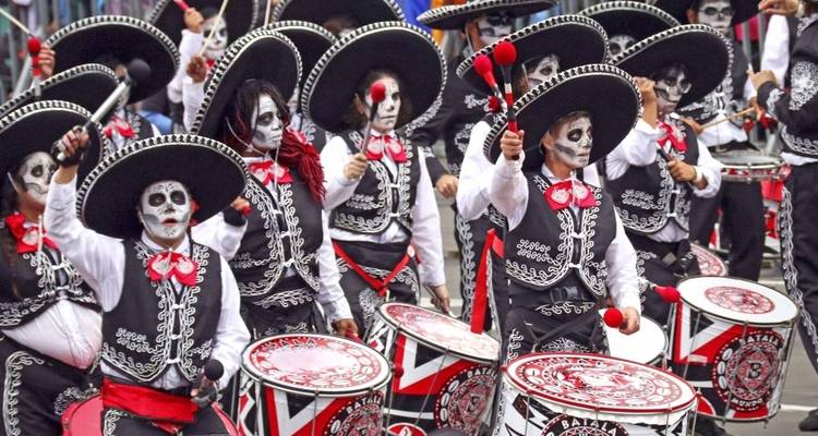 Mensen in traditionele kostuums met gezichtsbeschildering en instrumenten, waarschijnlijk op een festival of parade.
