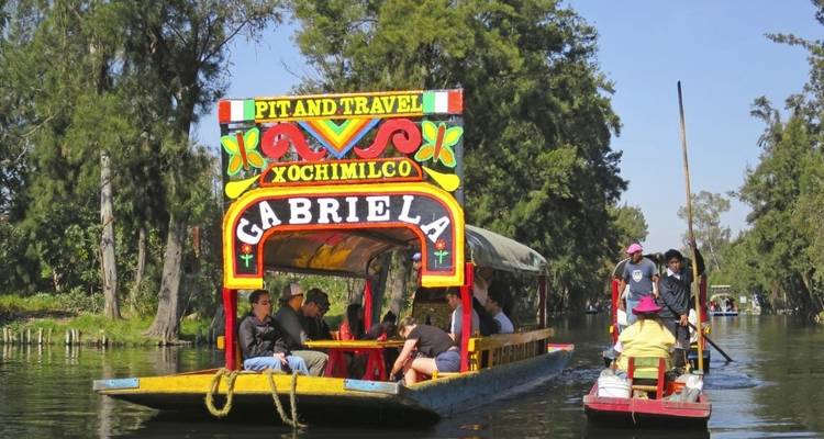 Kleurrijke boten op een kanaal met mensen erin, mogelijk Xochimilco.