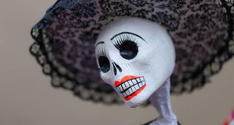 Een decoratieve schedel met een zwarte kanten hoed, representatief voor Dia de los Muertos.