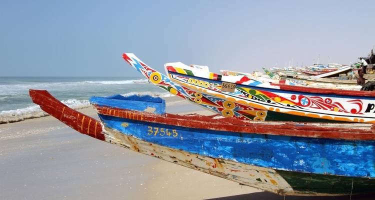 Brightly colored fishing boats on a sandy beach.