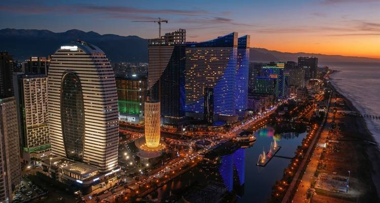 Paisaje urbano de edificios modernos iluminados por la noche junto al agua.