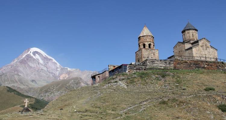 Iglesia en la cima de una colina con montañas al fondo.