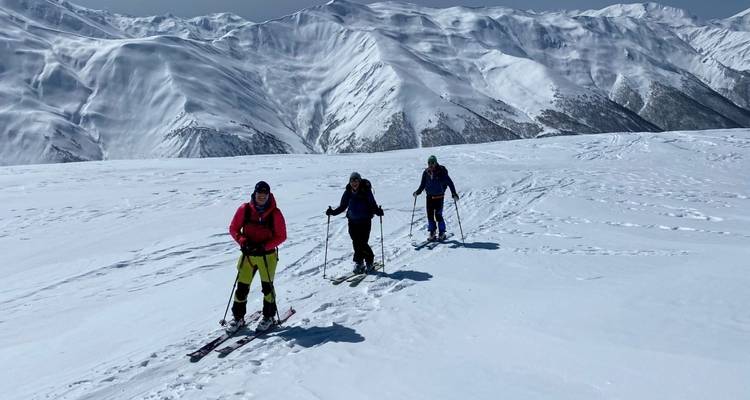 Tres esquiadores en una vasta montaña nevada.
