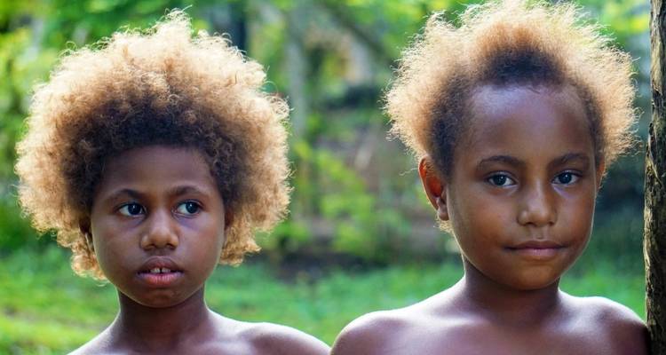 Two children with distinctive hairstyles in a natural setting.