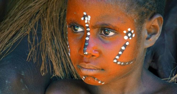 A child with face paint in a tribal setting.