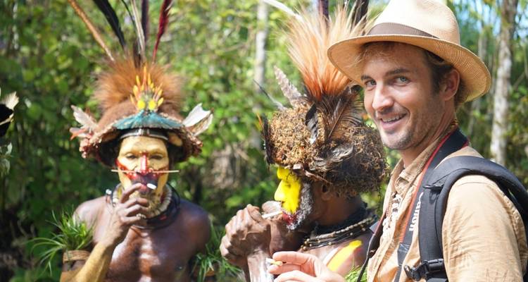A tourist interacting with local tribesmen wearing traditional attire.
