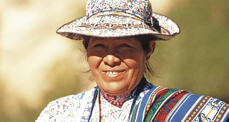 Smiling woman in traditional attire with colorful textiles.