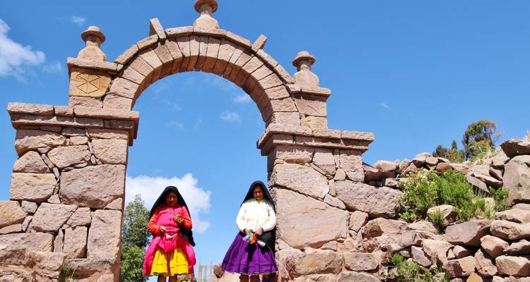 Two women in traditional dress under a stone arch.
