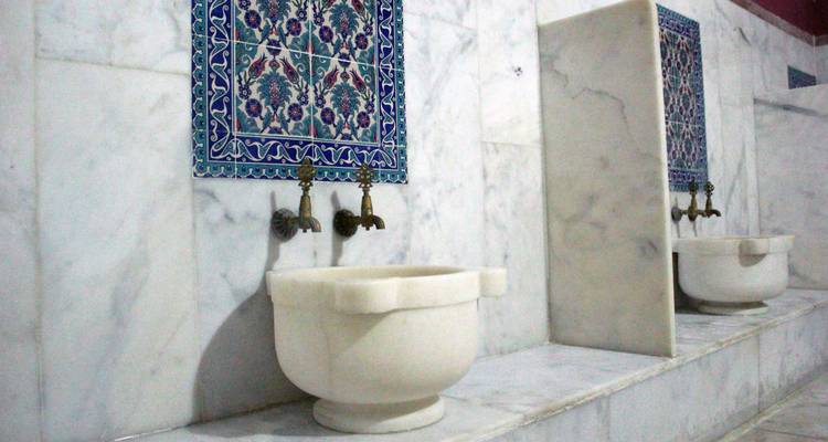 Traditionelle Marmorwaschbecken mit verzierten Wasserhähnen in einem türkischen Bad.