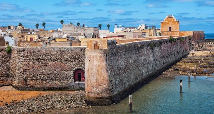 Alte befestigte Mauern an einer Küste mit ruhigem Wasser.