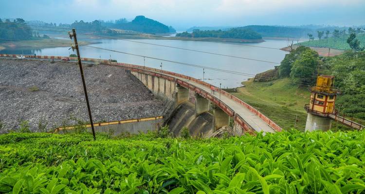 Ein Damm mit Blick auf einen ruhigen See, umgeben von Hügeln.