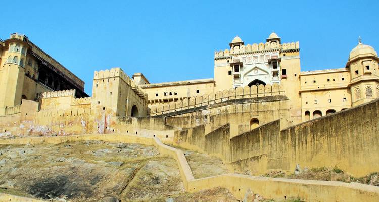 Amber Fort’s pale-yellow ramparts rise above a rocky hillside under a bright blue sky.