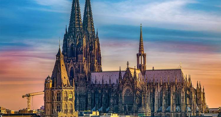 Cologne Cathedral silhouetted against a colourful sunset sky.