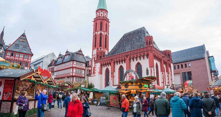 Festive Christmas market scene in Frankfurt's Römerberg with colourful stalls and crowds.