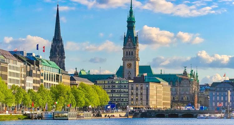 Skyline of Hamburg with the historic Rathaus and church spires reflected in the Alster lake.