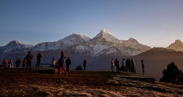 Gruppe von Menschen, die eine malerische Aussicht auf Berge bei Sonnenuntergang genießt.