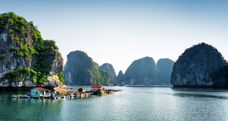 Baie pittoresque avec maisons flottantes et falaises calcaires.