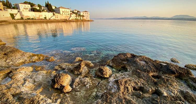 Une scène côtière avec une eau cristalline et des bâtiments traditionnels au coucher du soleil.