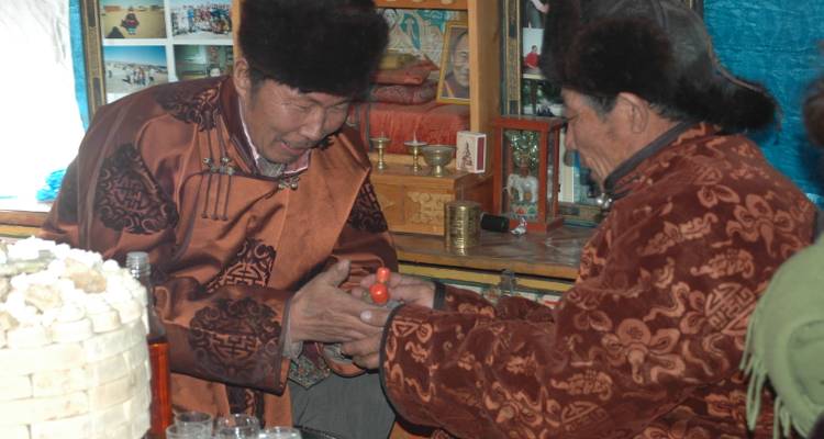 Zwei Männer in traditioneller mongolischer Kleidung, die an einer kulturellen Aktivität teilnehmen.