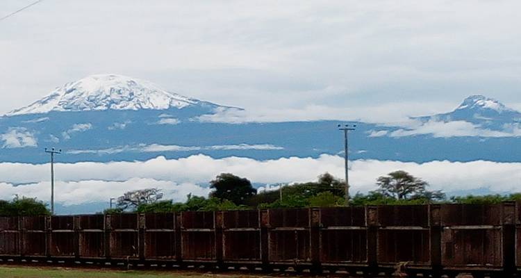 Berggipfel mit Schnee und Wolken unter einem bewölkten Himmel.