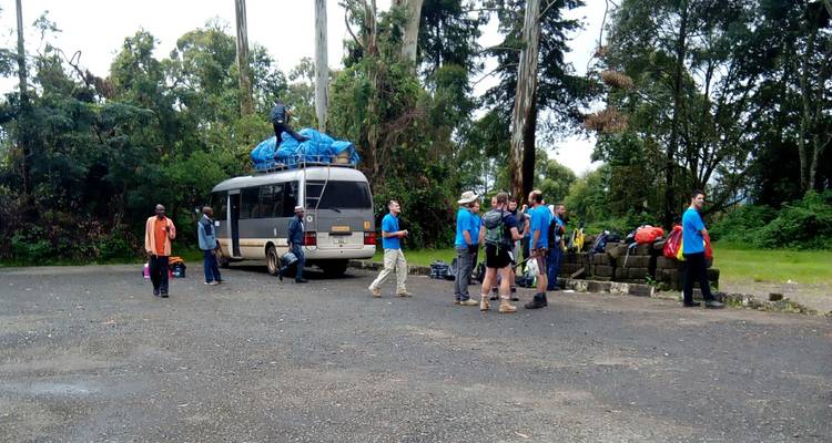 Gruppe von Menschen, die sich um einen Lieferwagen mit Vorräten auf einem gepflasterten Bereich versammelt.