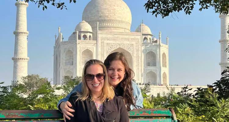 Zwei Frauen lächeln mit dem Taj Mahal im Hintergrund.