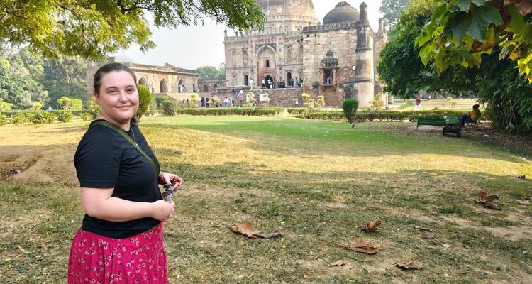 Frau in einem Garten mit historischer Architektur im Hintergrund.