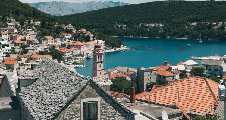 Vue panoramique d'une ville au bord d'une baie avec des collines en arrière-plan.