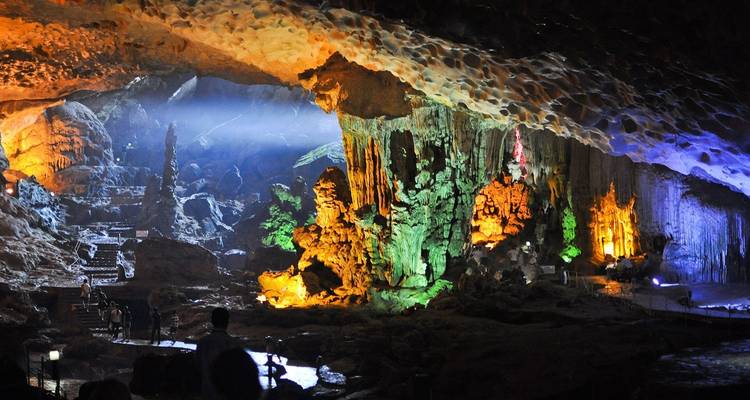 Bunt beleuchtetes Höhleninneres mit Stalaktiten und Stalagmiten.