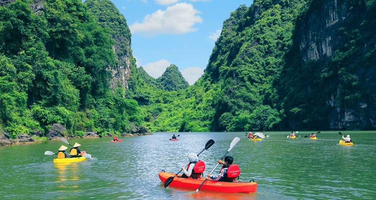 Kajakfahrer in lebendigen Gewässern, umgeben von üppigen Bergen.