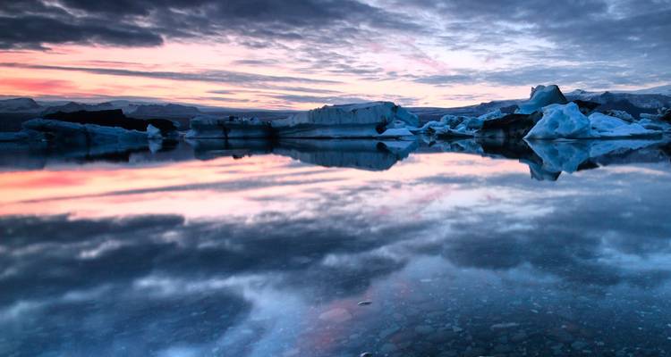 Icebergs reflectantes bajo un cielo crepuscular colorido en la laguna de Jokulsarlon.