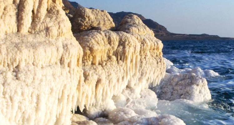 Formations de sel près de la mer Morte avec de l'eau en arrière-plan.