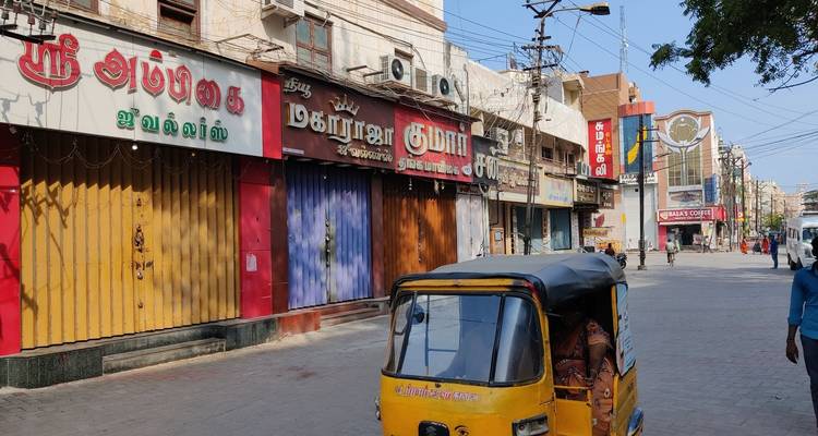 Straßenansicht mit bunten geschlossenen Geschäften und einer Autoriksha.