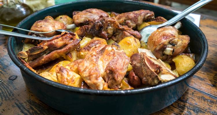 Traditional Croatian peka of roasted meat and potatoes in a rustic pan.