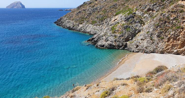 Paysage côtier avec une eau bleue claire et des falaises rocheuses.
